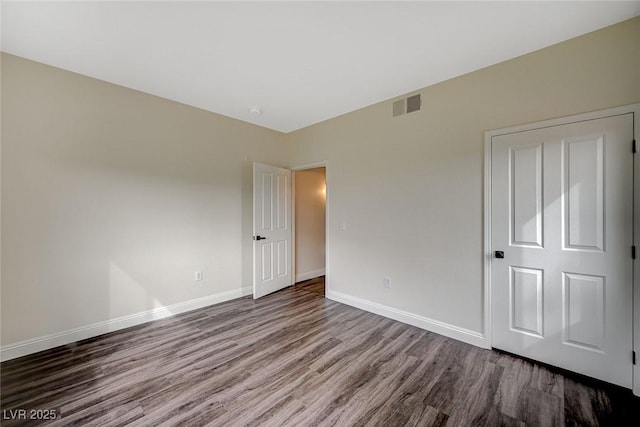 unfurnished bedroom featuring wood finished floors, baseboards, and visible vents