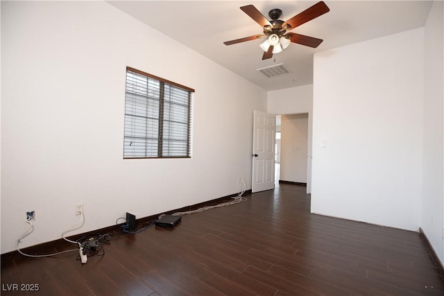 spare room featuring a ceiling fan, visible vents, dark wood-style flooring, and baseboards