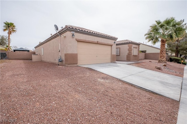 view of front of home with fence, stucco siding, concrete driveway, a garage, and a tiled roof