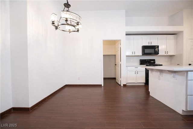 kitchen featuring dark wood-type flooring, a notable chandelier, black appliances, white cabinets, and light countertops