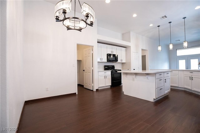 kitchen featuring dark wood finished floors, light countertops, a kitchen breakfast bar, white cabinets, and black appliances