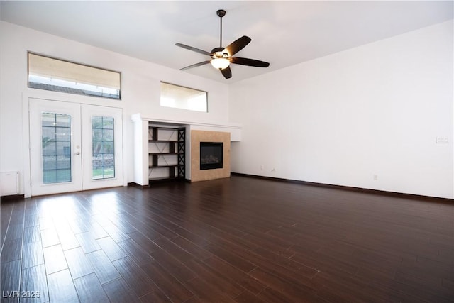 unfurnished living room with a glass covered fireplace, baseboards, dark wood-type flooring, and a ceiling fan