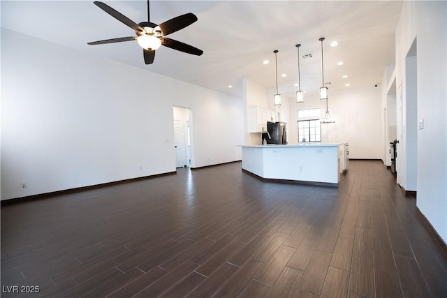 unfurnished living room featuring a ceiling fan, visible vents, baseboards, recessed lighting, and dark wood-type flooring