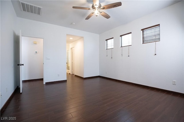 unfurnished room with visible vents, baseboards, dark wood-type flooring, and a ceiling fan