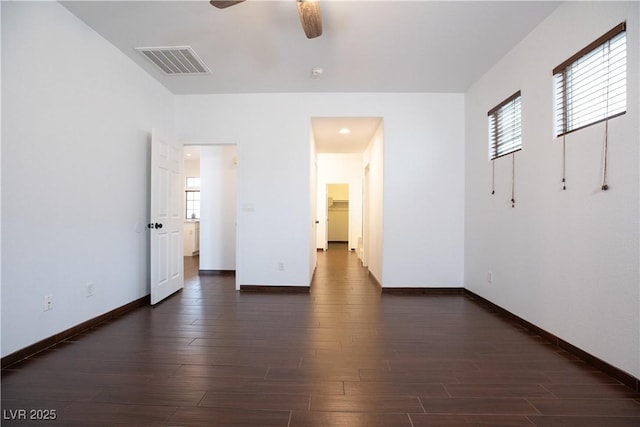 spare room featuring a ceiling fan, visible vents, dark wood-style flooring, and baseboards