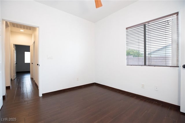 empty room featuring visible vents, baseboards, dark wood finished floors, and a ceiling fan