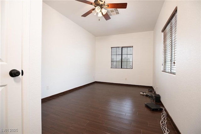 empty room with dark wood finished floors, visible vents, baseboards, and ceiling fan