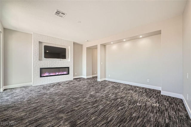 unfurnished living room with visible vents, baseboards, a premium fireplace, and carpet flooring