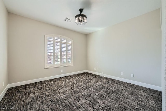 empty room with visible vents, baseboards, and dark carpet