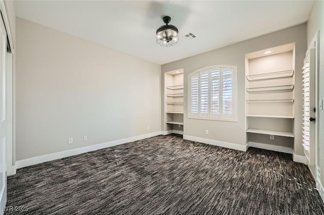 unfurnished bedroom with dark colored carpet, visible vents, and baseboards