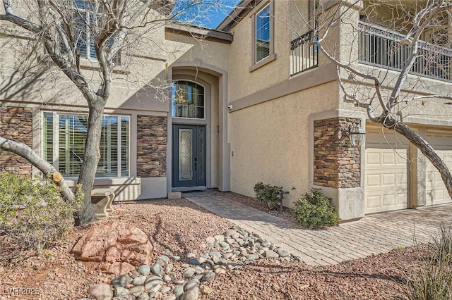 doorway to property with stone siding, stucco siding, and an attached garage