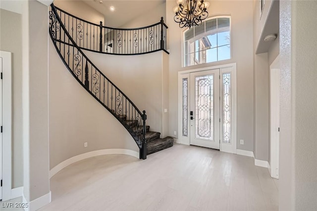 foyer featuring stairway, a high ceiling, an inviting chandelier, and wood finished floors