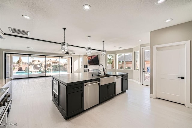 kitchen featuring visible vents, open floor plan, plenty of natural light, stainless steel appliances, and dark cabinets