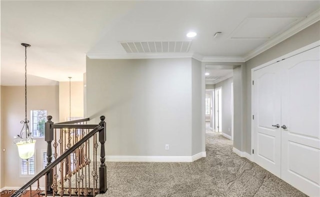 corridor with visible vents, baseboards, ornamental molding, an upstairs landing, and carpet flooring