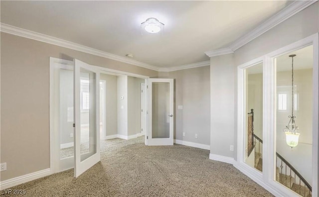 carpeted spare room with crown molding, french doors, and baseboards