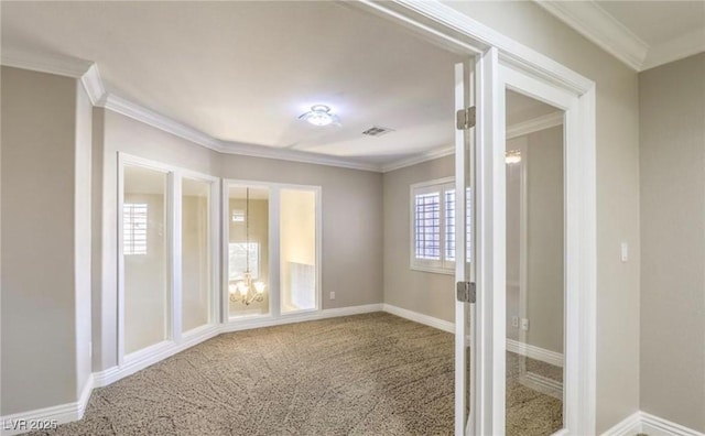 carpeted spare room with crown molding, baseboards, visible vents, and a chandelier