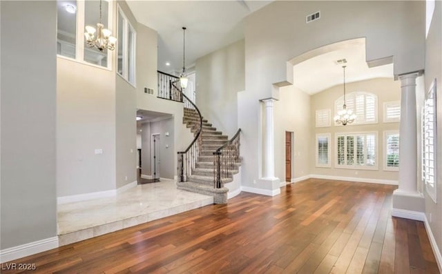 foyer with an inviting chandelier, hardwood / wood-style flooring, visible vents, and ornate columns