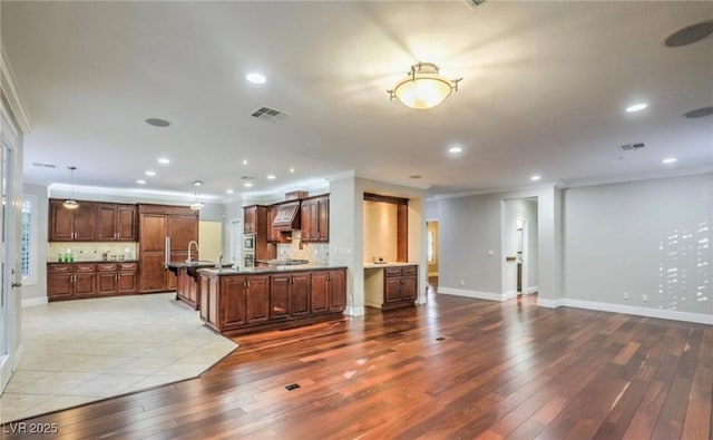 kitchen featuring open floor plan, ornamental molding, visible vents, and hardwood / wood-style flooring