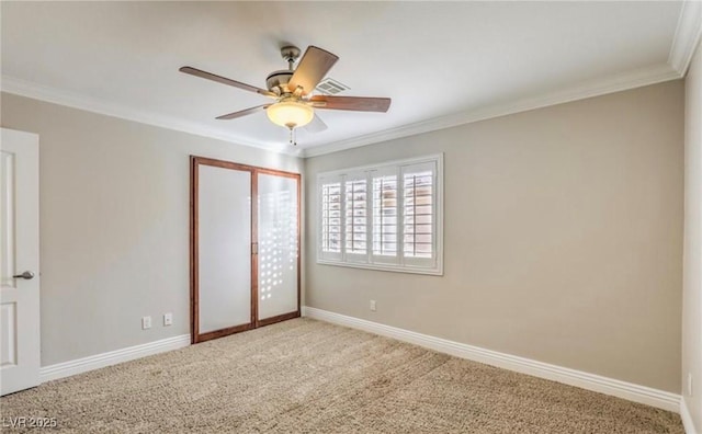 unfurnished bedroom with a ceiling fan, a closet, carpet flooring, crown molding, and baseboards