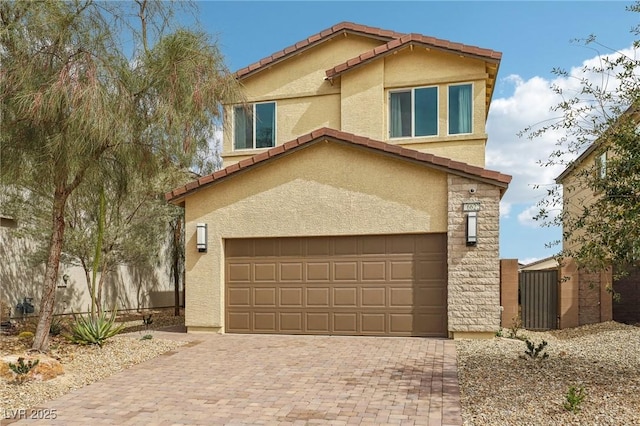 view of front of house featuring decorative driveway, a tile roof, an attached garage, and stucco siding