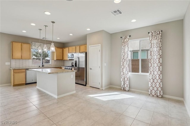 kitchen with visible vents, light brown cabinets, backsplash, a kitchen island, and appliances with stainless steel finishes