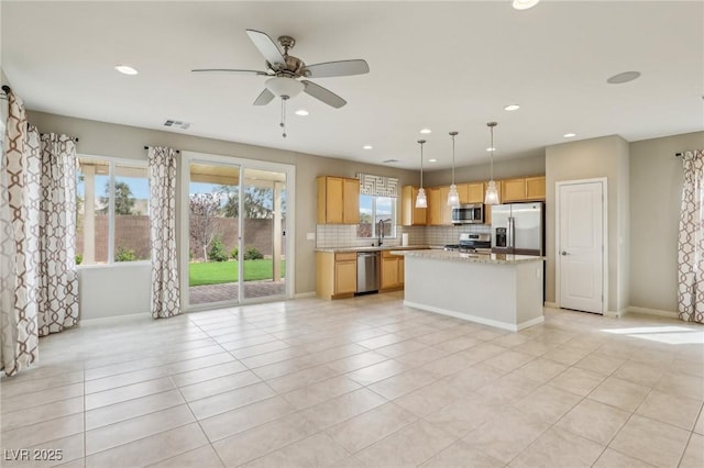 kitchen featuring backsplash, a center island, ceiling fan, appliances with stainless steel finishes, and light tile patterned flooring