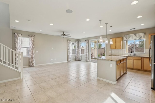 kitchen with tasteful backsplash, light tile patterned floors, a center island, and visible vents