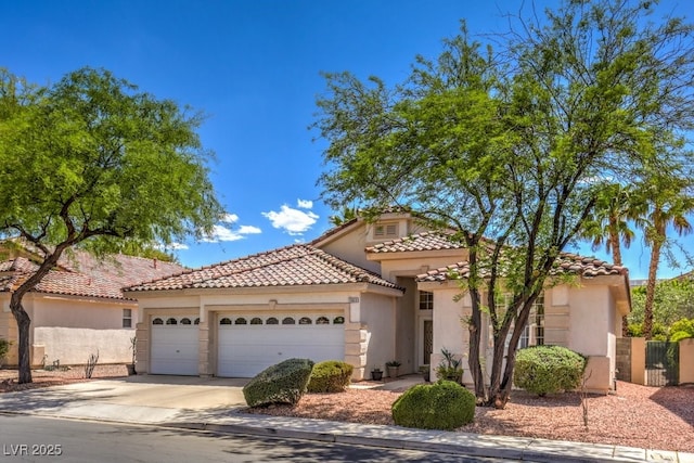 mediterranean / spanish home featuring a tiled roof, stucco siding, an attached garage, and concrete driveway