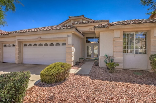 mediterranean / spanish-style home featuring a garage, a tile roof, driveway, and stucco siding