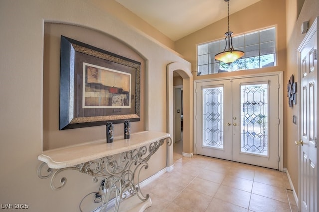 entrance foyer with french doors, baseboards, high vaulted ceiling, and light tile patterned flooring