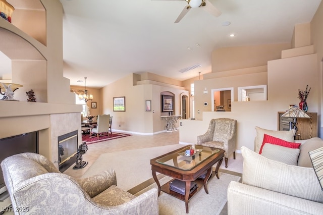 living area with visible vents, baseboards, light colored carpet, vaulted ceiling, and ceiling fan with notable chandelier