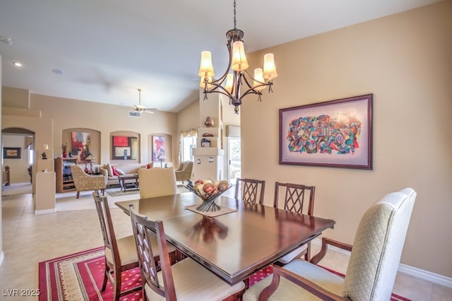 dining room featuring light tile patterned floors, arched walkways, lofted ceiling, and ceiling fan with notable chandelier