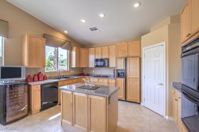 kitchen featuring black appliances, light brown cabinets, a sink, a kitchen island, and light tile patterned floors