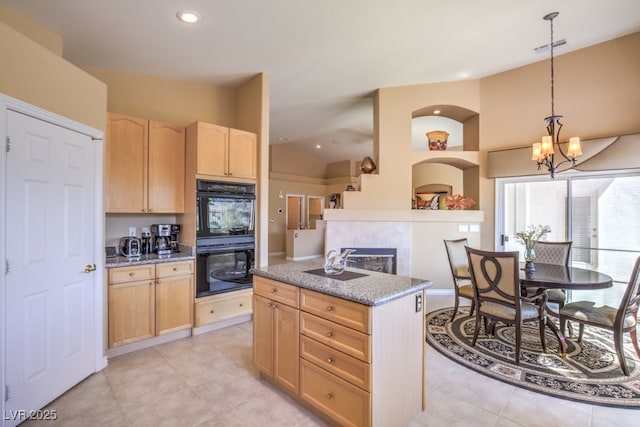 kitchen featuring visible vents, light brown cabinetry, decorative light fixtures, lofted ceiling, and dobule oven black