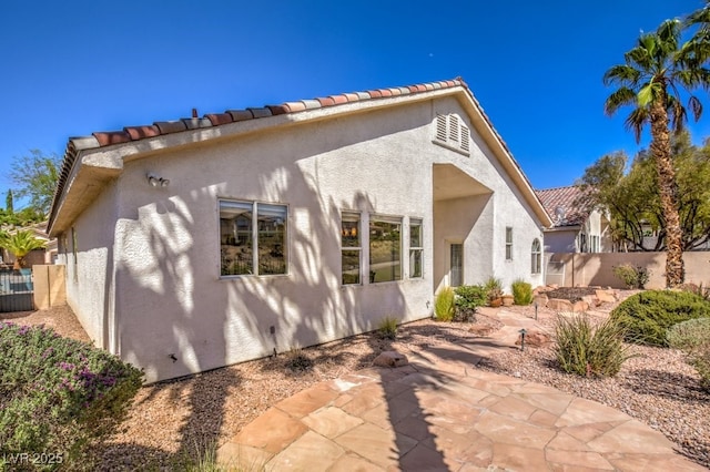 back of house with a patio, a tiled roof, fence, and stucco siding