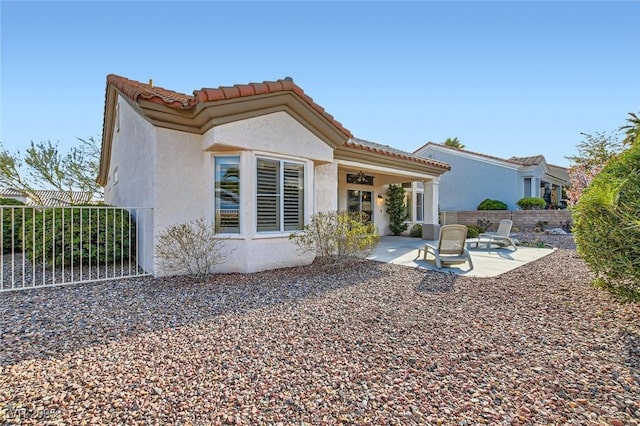 rear view of house with a patio area, stucco siding, a tile roof, and fence