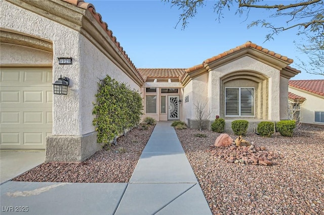 doorway to property with stucco siding, a tiled roof, and a garage