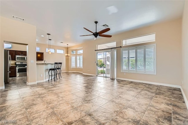 unfurnished living room with visible vents, baseboards, and ceiling fan