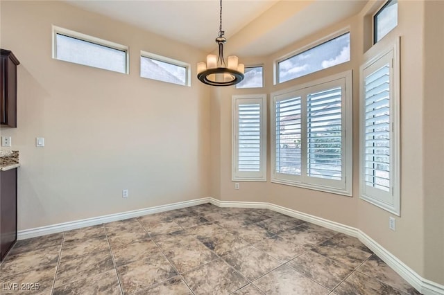 unfurnished dining area featuring baseboards and a chandelier