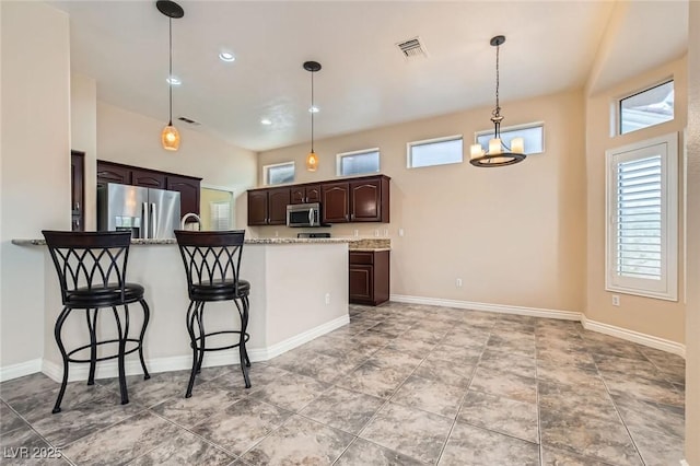 kitchen with visible vents, stainless steel appliances, a breakfast bar area, dark brown cabinets, and a healthy amount of sunlight