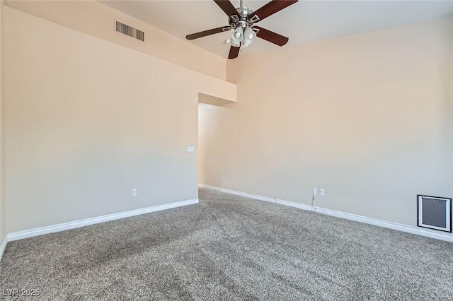 carpeted spare room featuring baseboards, visible vents, and ceiling fan