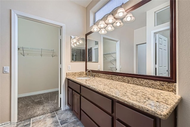 bathroom featuring a chandelier, vanity, a walk in closet, and baseboards