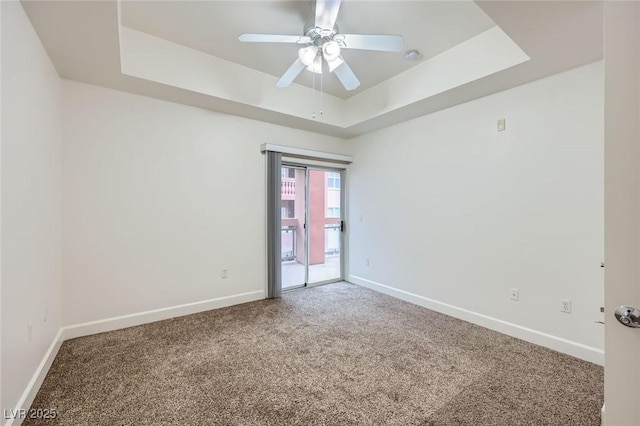 empty room featuring ceiling fan, baseboards, a raised ceiling, and carpet