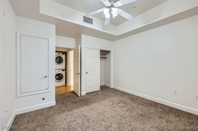 unfurnished bedroom with stacked washer / dryer, carpet flooring, baseboards, and visible vents