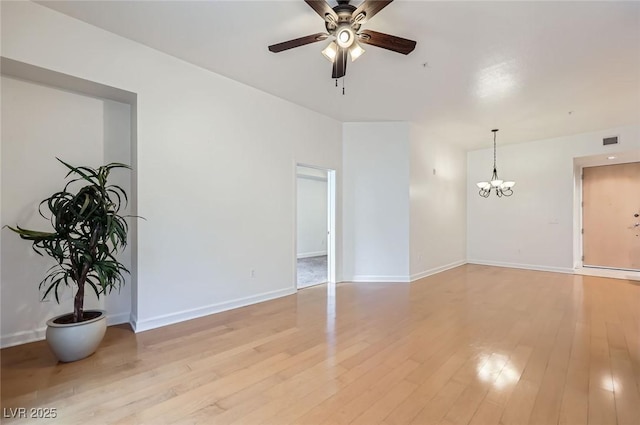 spare room with ceiling fan with notable chandelier, light wood-style floors, visible vents, and baseboards