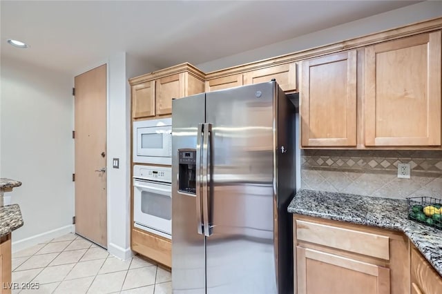 kitchen with white appliances, light tile patterned floors, light brown cabinets, and tasteful backsplash