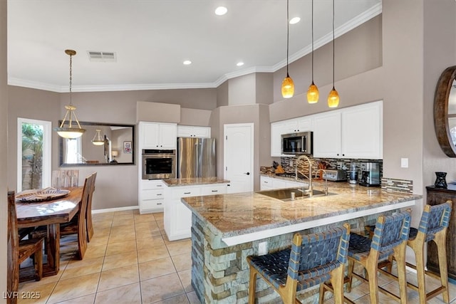 kitchen featuring visible vents, a peninsula, ornamental molding, stainless steel appliances, and backsplash