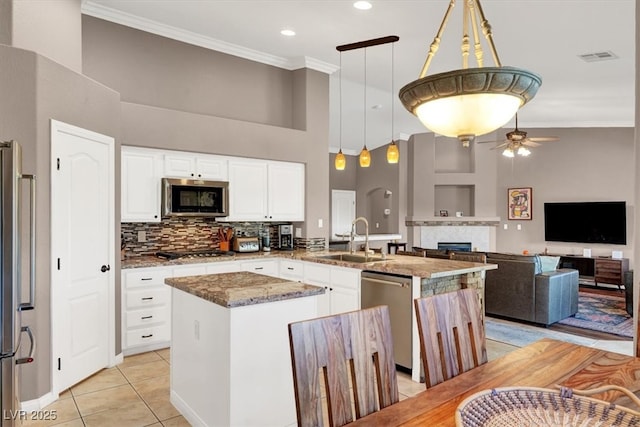 kitchen featuring crown molding, ceiling fan, stone counters, stainless steel appliances, and a sink