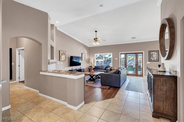 living room featuring baseboards, ornamental molding, light tile patterned floors, french doors, and a ceiling fan