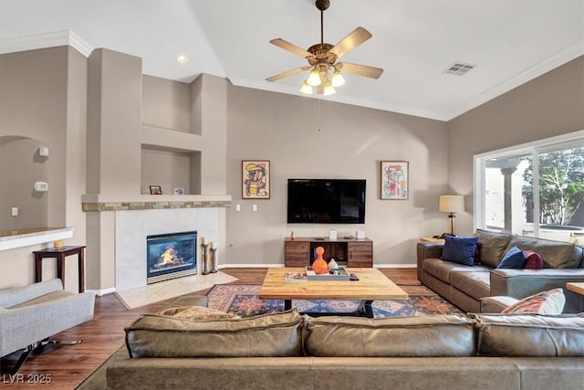 living room with crown molding, wood finished floors, visible vents, and ceiling fan